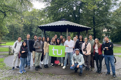 Eine Gruppe von internationalen Studierenden steht vor einem kleinen Unterstand im Fredenbaumpark