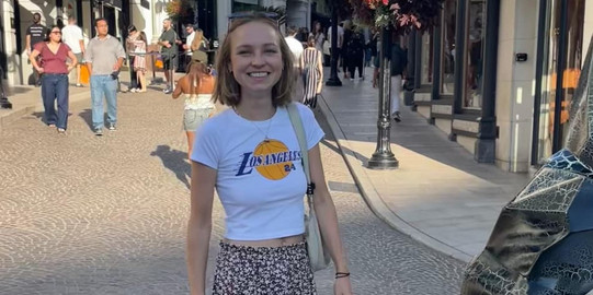 Carla Carla läuft auf einer geplasterten Straße. Im Hintergrund erkennt man viele kleine Geschäfte.