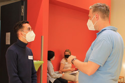 Tandem4Talking Mentee (links) im Gespräch mit Mentor (rechts); im Hintergrund zwei Personen