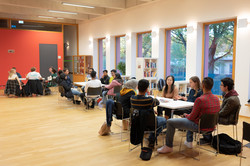 Sprachcafé_8 International students sit at group tables in the IBZ and talk.