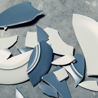 Zerbrochener Teller auf grauem Boden.