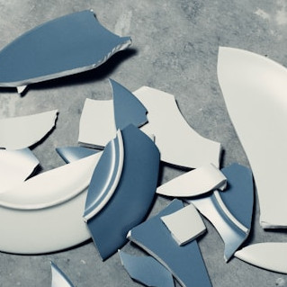 Zerbrochener Teller auf grauem Boden.