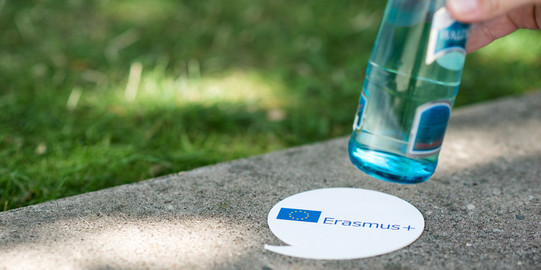 Untersetzer Erasmus+ Ein Untersetzer mit dem Schriftzug "Erasmus+" unter einer Flasche Wasser