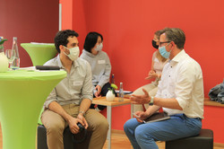 TwoTandemsTalking Vier Personen sitzten und sind jeweils zu zweit im Gespräch