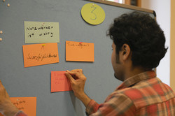 Midterm Meeting Tandem2Job Brainstorming: Mann pinnt Karte an Pinnwand