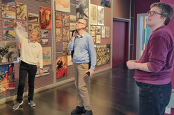 Menschen schauen auf Bilder an Stellwänden.