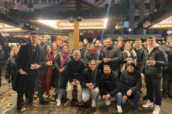 Sprachcafé auf dem Weihnachtsmarkt, 2023 Auf dem Bild sieht man eine Gruppe Studierender, die zusammen an einem Stand auf dem Weihnachtsmarkt stehen.