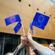 EU flags People standing in a circle and holding small EU flags up high