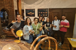 Menschen stehen vor den Kupferkesseln einer Brauerei.