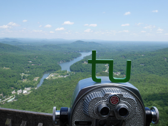 Traveling_TU_Lake_Lure TU Logo auf einem Fernglas mit Blick zu einer Flusslandschaft
