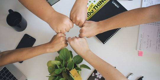 Zusammenhalt Diverse Menschen halten ihre Fäuste zum Zeichen des Zusammenhalts aneinander.