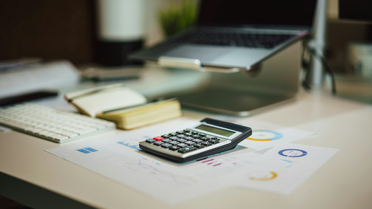 Ein Taschenrechner, ein Laptop und Formulare.