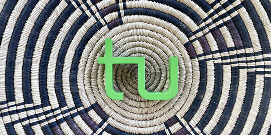 Makuleke Korb das TU Logo liegt auf einem Korb mit einem schwarz-braunen afrikanischenMuster