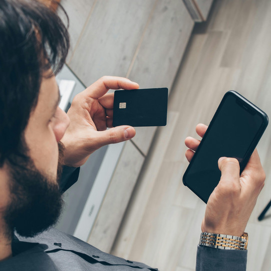 Ein Mann der eine Bankkarte und ein Handy in den Händen hält
