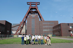 Eine Gruppe von Menschen vor dem Förderturm der Zeche Zollverein.