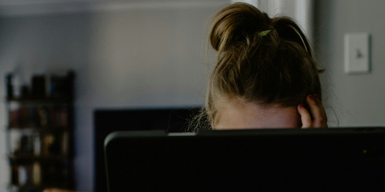Woman sitting hidden behind a laptop