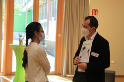 Tandem3Talking Mentee (Links) im Gespräch mit Mentor (rechts); Mentor hält Mentoring-Leitfaden in Hand