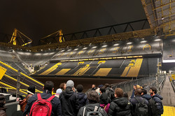 Menschen schauen von der Tribüne in ein Fußballstadion.