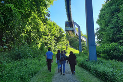 Menschen laufen unter der H-Bahn her.