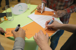 Midterm Meeting Tandem2Job 2024 Fokus auf die Hände von drei Personen, die Karten schreiben